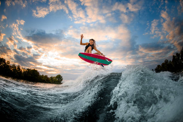 Une rideuse en wakesurf décollant au-dessus de la vague creusée par le bateau